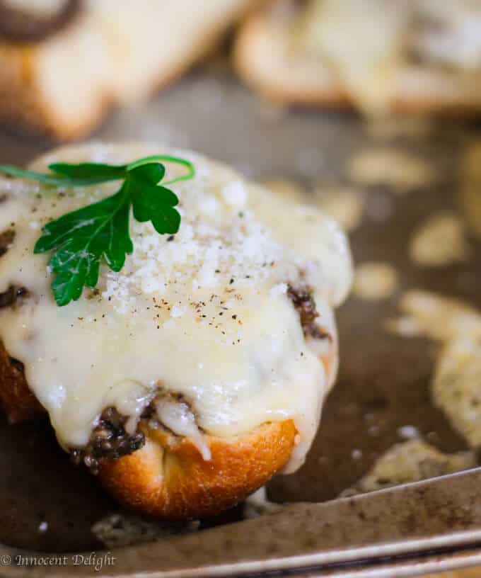 Toasts with Mushroom Pesto and Fontina Cheese on a baking sheet. 