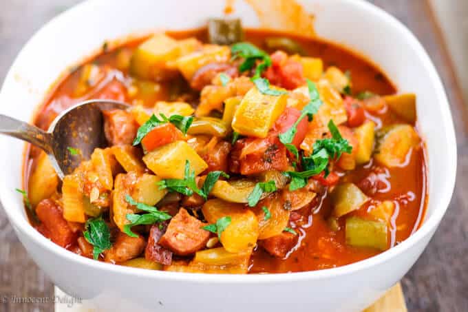 This tomato and peppers stew (Hungarian Lecho or Lescho) dish uses the freshest summer ingredients like ripe tomatoes, green and banana peppers and luscious zucchinis. When it simmers, the house smells incredible. Tomato and Peppers Stew in a bowl with spoon