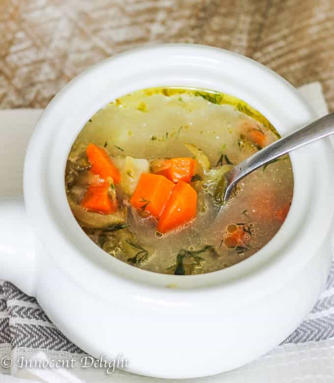 This Dill Pickle Soup (or "Zupa Ogorkowa" in Polish) is the most popular Polish soup of them all. Here, you will find a traditional Polish recipe for pickle soup. For some it may sound strange, but if most Polish kids love it, then there must be something to it. Pickle soup in a white bowl with spoon inside, standing on a kitchen towel