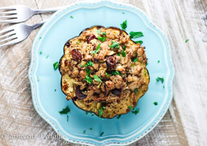 This Turkey Stuffed Acorn Squash with Apples, Cranberries & dried Thyme are irresistible with all the fall flavors in one dish. Turkey Stuffed Acorn Squash on a blue plate