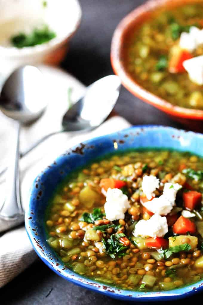 Bowls of Greek lentils soup with feta with spoons on a side