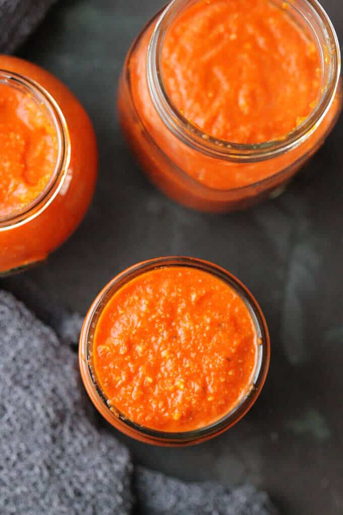 Romesco Sauce - famous Spanish sauce with roasted peppers, tomatoes, onions, garlic, almonds, bread, olive oil, vinegar, and Spanish Smoked Paprika. Easy and delicious. Overhead photo of Romesco sauce in mason jars