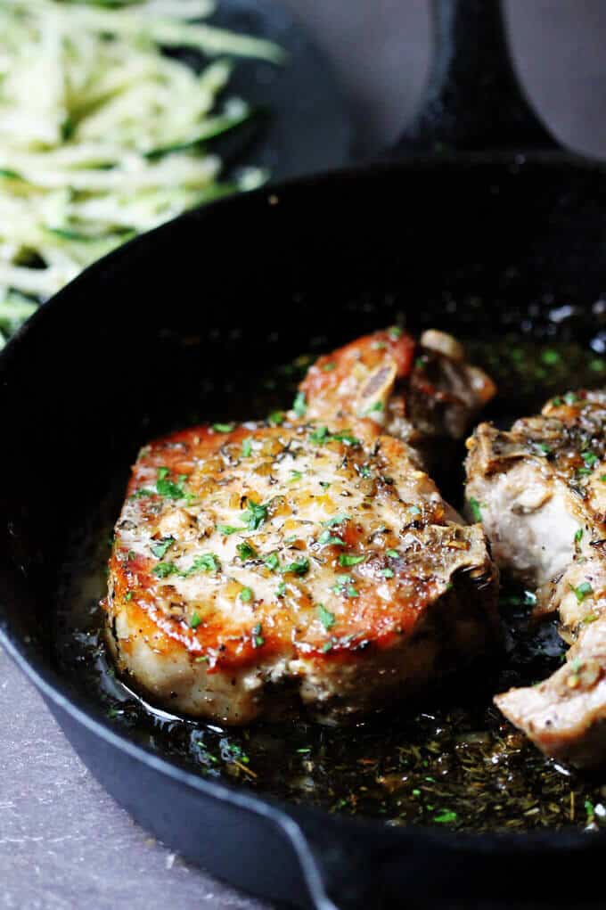 Brown Sugar Pork Chops with Garlic and Herbs are as delicious as they sound. The sweet brown sugar sauce is perfectly balanced by garlic and dried herbs like thyme and oregano. Juicy pork chops dish that comes together in no time. Brown sugar pork chops in a skillet with zucchini noodles on a plate