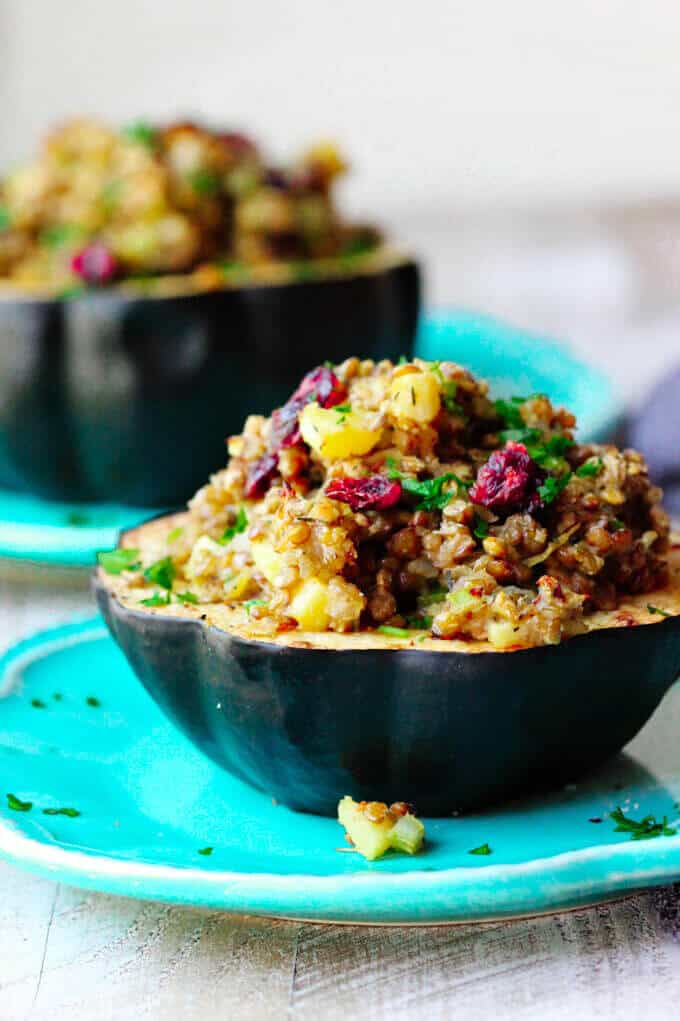 Lentils Stuffed Acorn Squash with apples, dried cranberries and thyme is a perfectly balanced vegetarian dish that combines all of your favourite fall flavors in every bite. Lentils stuffed acorn squash half on blue plate