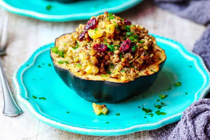 Lentils Stuffed Acorn Squash with apples, dried cranberries and thyme is a perfectly balanced vegetarian dish that combines all of your favourite fall flavors in every bite. Lentils Stuffed Acorn half Squash with apples and dried cranberries on a blue plate