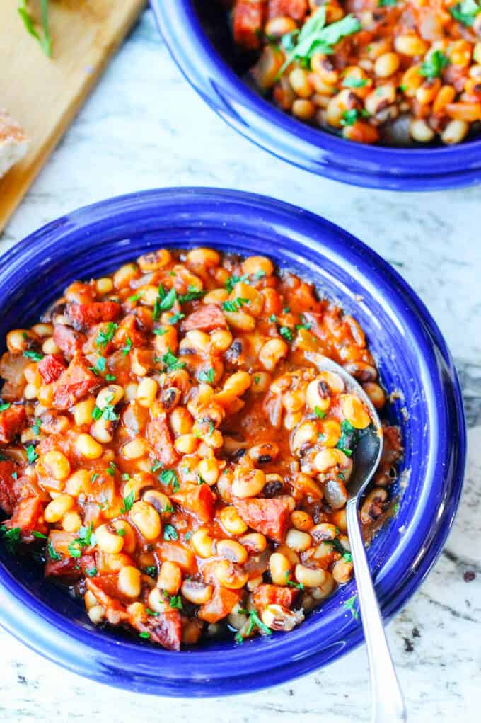 beans with sausage and tomatoes on blue plate with spoon