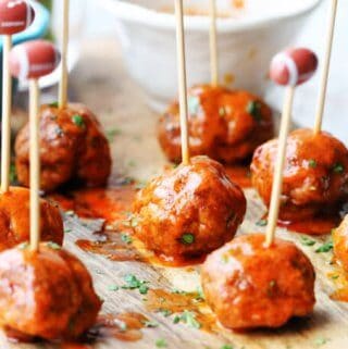 Buffalo Turkey Meatballs with football sticks and bowls with sauces in the back, vertical