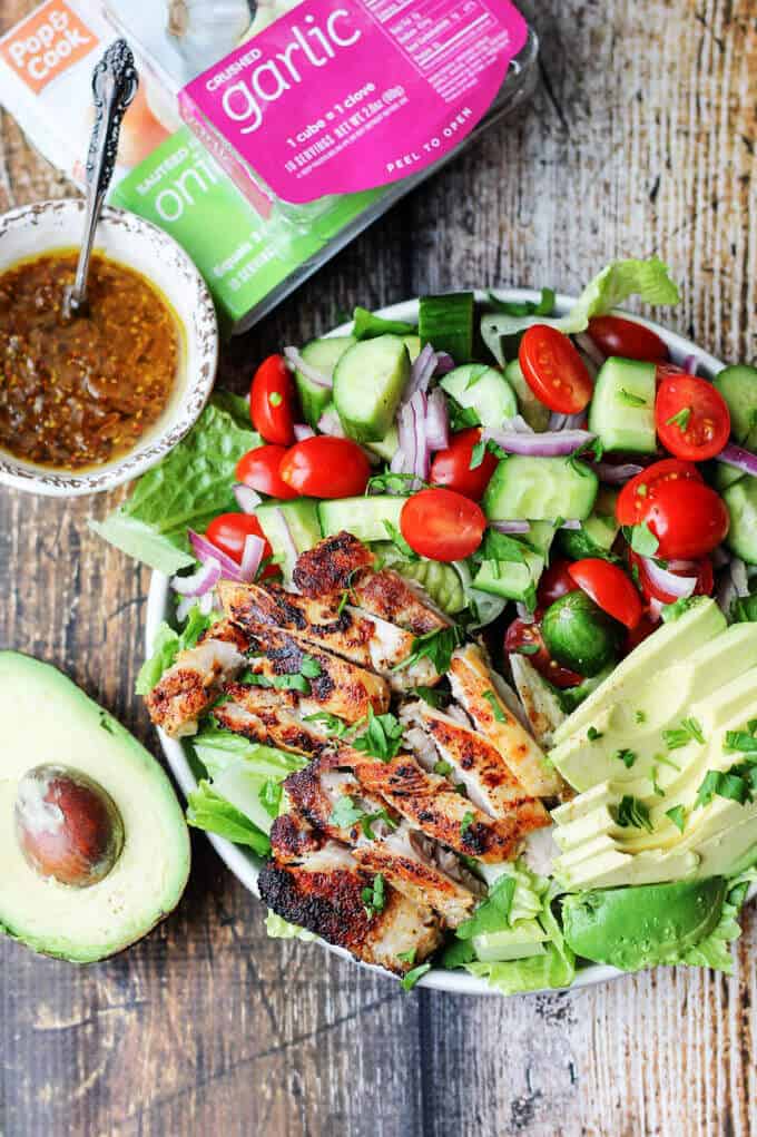 Garlic Lemon Chicken Salad on lettuce on a plate; side of dressing in a bowl