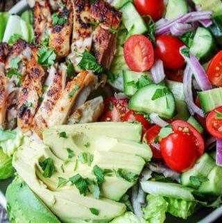 Garlic Lemon Chicen Salad with lettuce, tomatoes, cucumber, onions, avocado; vertical