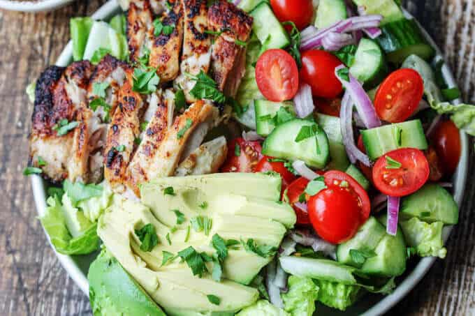 Garlic Lemon Chicen Salad with lettuce, tomatoes, cucumber, onions, avocado; vertical