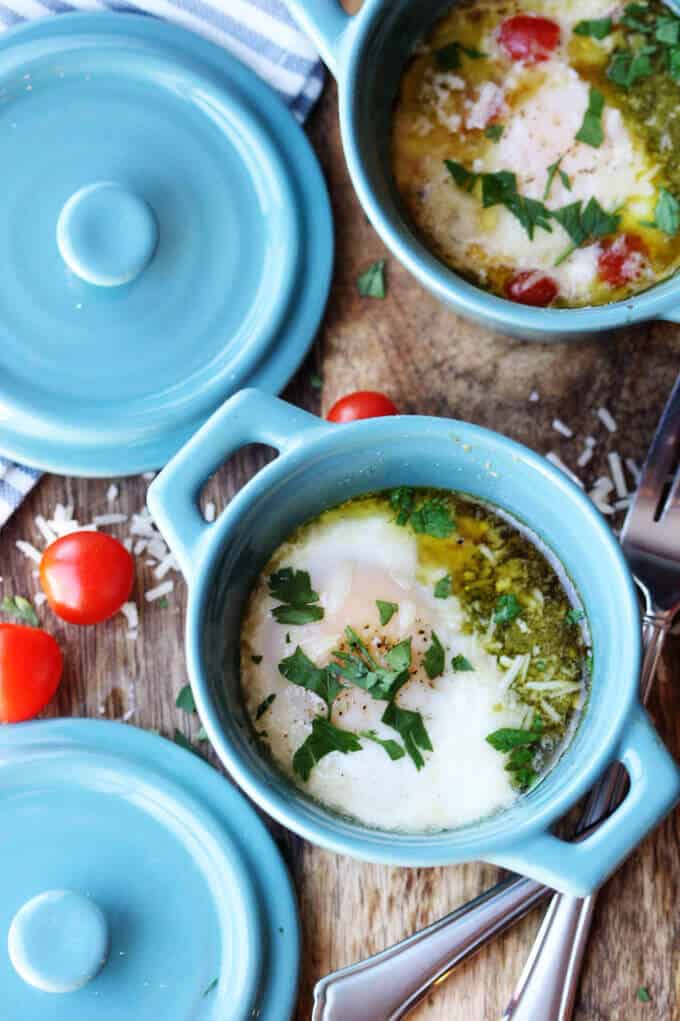 These Baked Eggs with Tomatoes and Pesto can be added to your ketogenic breakfast menu if you are looking for low carb recipes. It's super quick, delicious, naturally low in carbs and packed full of healthy fats. two ramekins with baked eggs with tomatoes and pesto