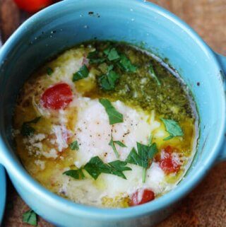 baked eggs with tomatoes and pesto in blue ramekin, horizontal shot