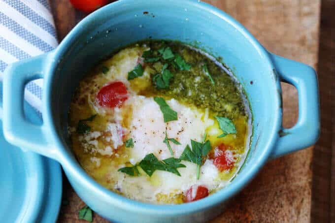 These Baked Eggs with Tomatoes and Pesto can be added to your ketogenic breakfast menu if you are looking for low carb recipes. It's super quick, delicious, naturally low in carbs and packed full of healthy fats. baked eggs with tomatoes and pesto in blue ramekin, horizontal shot