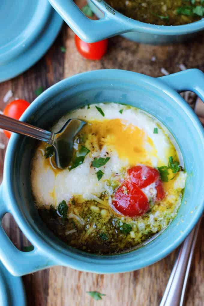 These Baked Eggs with Tomatoes and Pesto can be added to your ketogenic breakfast menu if you are looking for low carb recipes. It's super quick, delicious, naturally low in carbs and packed full of healthy fats. Baked eggs with tomatoes and pesto in blue ramekin with fork inside