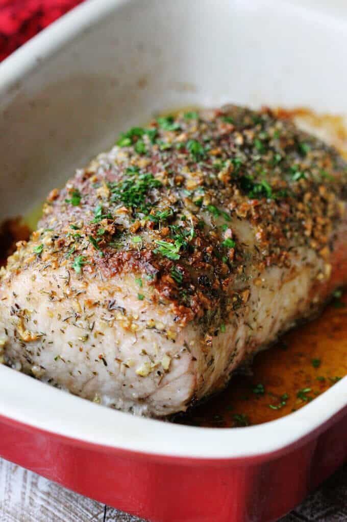 Brown sugar pork loin with garlic and herbs in red baking dish