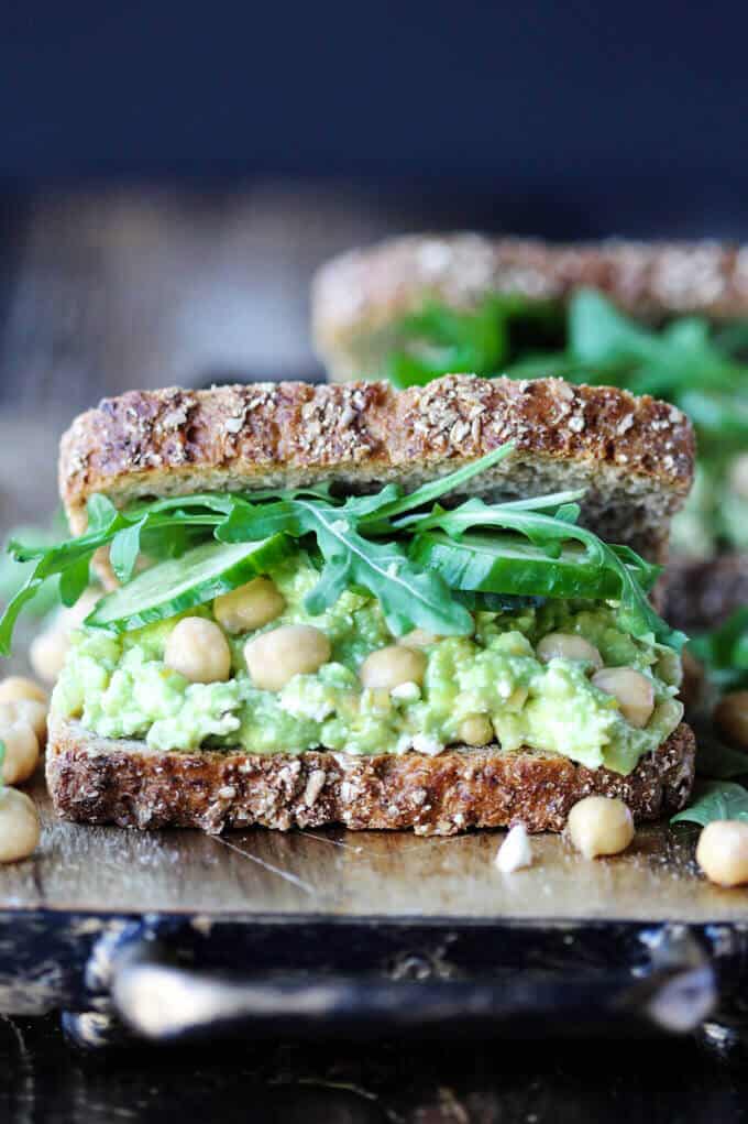 Smashed Chickpea Avocado Feta Sandwich with cucumber and arugula, front close up