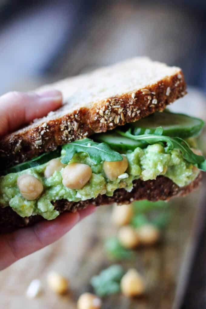 Smashed Chickpea Avocado Feta Sandwich held in hand