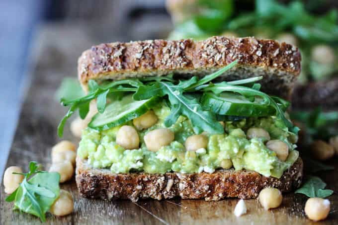 Smashed chickpea avocado feta sandwich on a cutting board