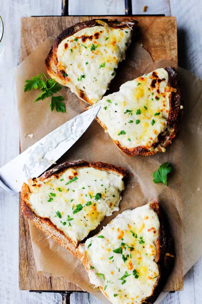 This Classic Croque Monsieur Recipe is easy to prepare and is a taste emersion right to the middle of Paris. For this recipe you can use any type of ham; so by all means, feel free to use any leftovers that you may have from this Easter. Croque Monsieur ham and cheese sandwich on a board with a knife