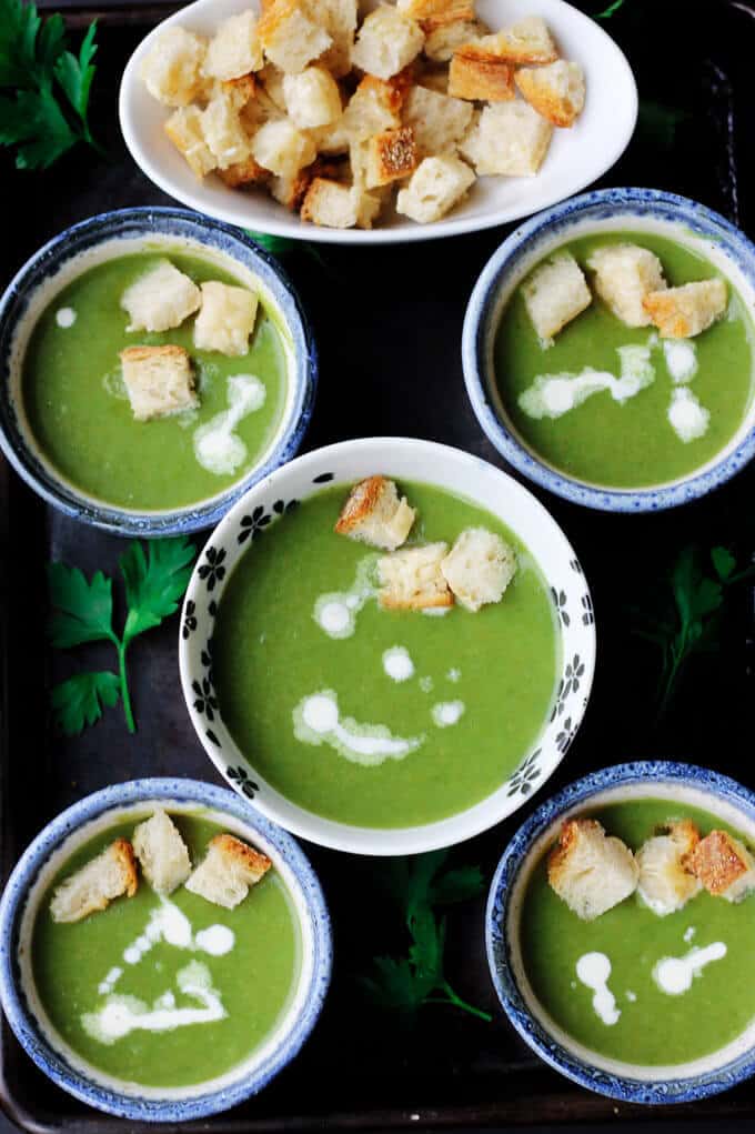 This Creamy Spinach Soup with Parmesan Croutons is very easy, healthy and by far the best spinach soup I've eaten. Not to mention, with a few simple substitutions it can even be transformed into a vegan soup. healthy creamy spinach soup in 5 bowls with croutons on a side and in the soups