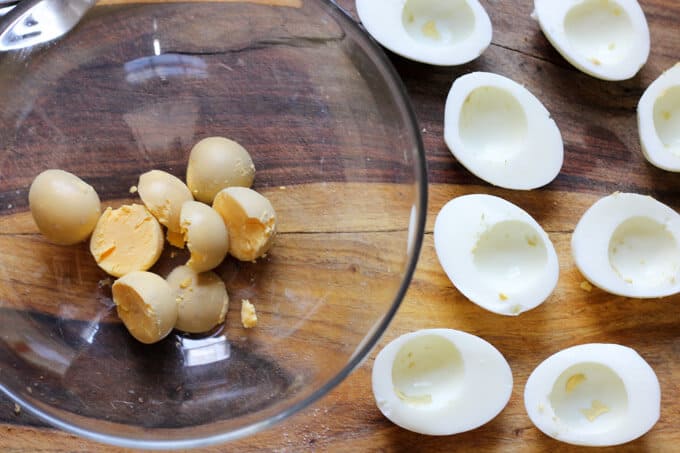 Stuffed Eggs with Ham & Cheese, sprinkled with a dash of Spanish Smoked Paprika, are super meaty, cheesy and satisfying. The subtle heat from the smoked paprika marries everything together to create a perfect egg bite. These are a MUST for your Easter table hard boiled eggs with egg yolks separated in a bowl and egg whites on a cutting board