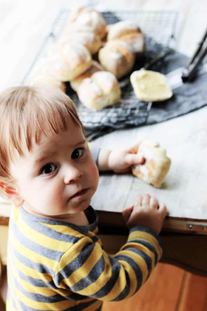 Child eating roll, with more rolls in the back
