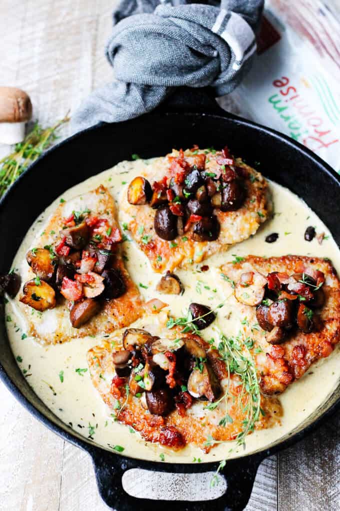 Pork Chops in withe wine cream sauce with mushrooms and bacon in the pan with bacon on a side