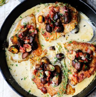 Pork chops in creamy white wine sauce with mushrooms and bacon in a pan, overhead, horizontal shot