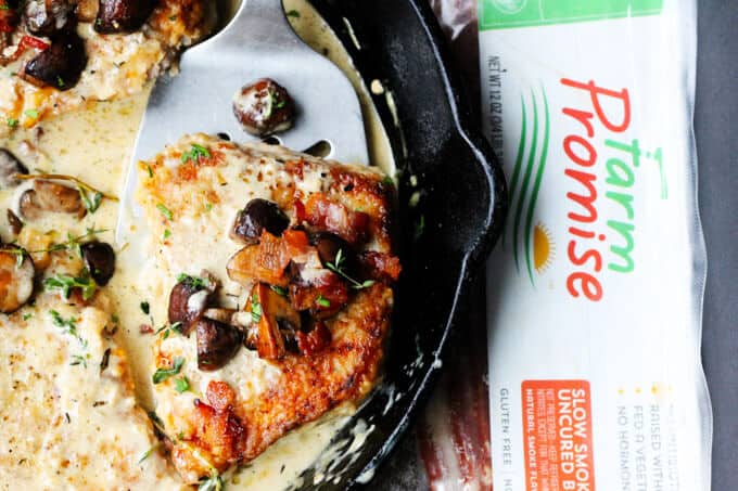 Pork chops in white wine cream sauce with mushrooms in a pan, bacon on a side