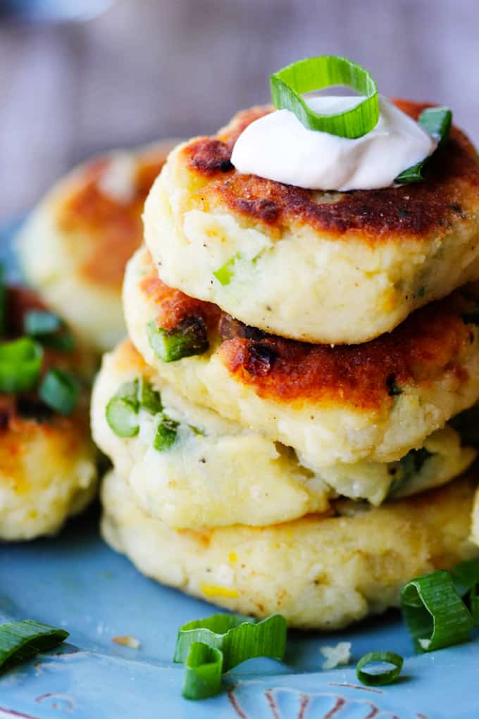 This recipe for Potato Cutlets with Asparagus is a keeper. In fact, the ease of preparation, coupled with deliciousness of the dish, might catapult this one into heavy rotation. Preparation just requires a few steps that and, again, the taste is amazing. Potatoes with asparagus - fried to perfection - and served with a dollop of sour cream and scallions. And while there are no breadcrumbs involved, they still achieve crispy and golden brown crust. Stack of potato cutlets with asparagus on a blue plate