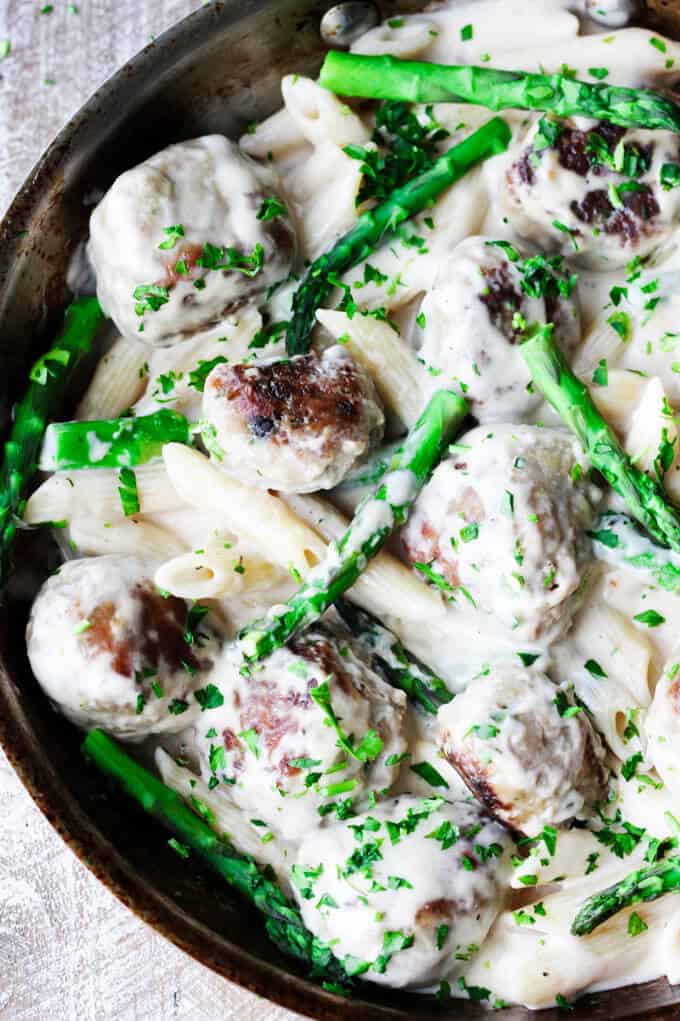 Turkey meatballs with asparagus in creamy alfredo sauce in a pan, overhead shot