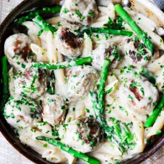 turkey meatballs and asparagus in creamy Alfredo sauce in a pan; overhead horizontal shot