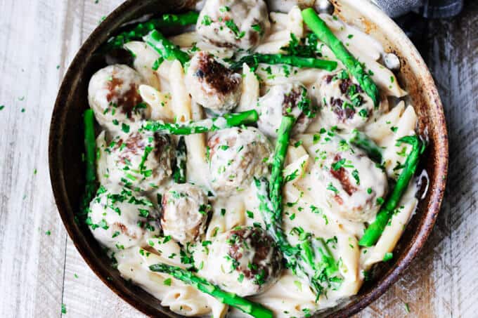 This Turkey Meatballs Alfredo Pasta with Asparagus is a perfect midweek dinner, for nights when you're short on time but still want to make your family a hearty meal. It comes together quickly and incorporates a store-bought Alfredo sauce shortcut. turkey meatballs and asparagus in creamy Alfredo sauce in a pan; overhead horizontal shot