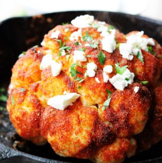 Whole roasted cauliflower head in a skillet