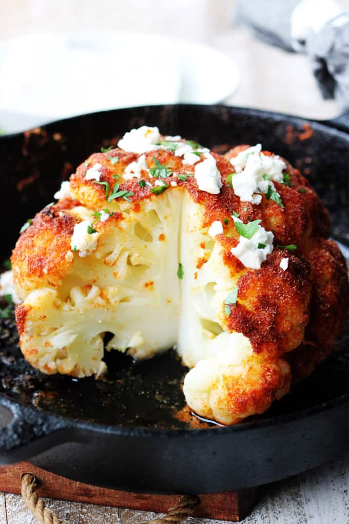 This Whole Roasted Cauliflower with Mediterranean spices and feta, drizzled with some lemon juice and sprinkled with parsley is very impressive, incredibly flavorful and very easy to prepare. If you want to impress your guests try this recipe. Cut up roasted head of cauliflower with feta and spices.
