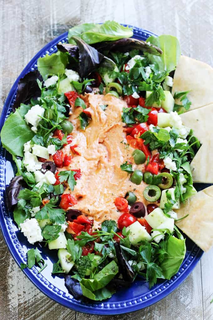 Hummus platter with vegetables and pita bread on blue plate