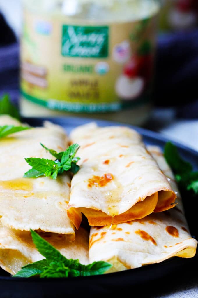These Apple Sauce Crepes with Honey Ricotta are made with cinnamon crepes, North Coast Organic Apple Sauce, organic ricotta and raw honey. These crepes are super delicious and healthy at the same time. A perfect option for a school lunch or even an afternoon snack. Crepes with Apple Sauce and Honey Ricotta on a plate
