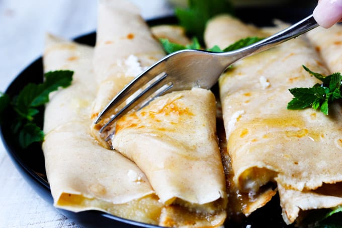 These Apple Sauce Crepes with Honey Ricotta are made with cinnamon crepes, North Coast Organic Apple Sauce, organic ricotta and raw honey. These crepes are super delicious and healthy at the same time. A perfect option for a school lunch or even an afternoon snack. Fork cutting through crepe with apple sauce and ricotta with honey