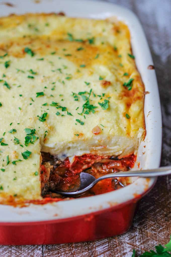 Vegetarian moussaka in red casserole dish with spoon
