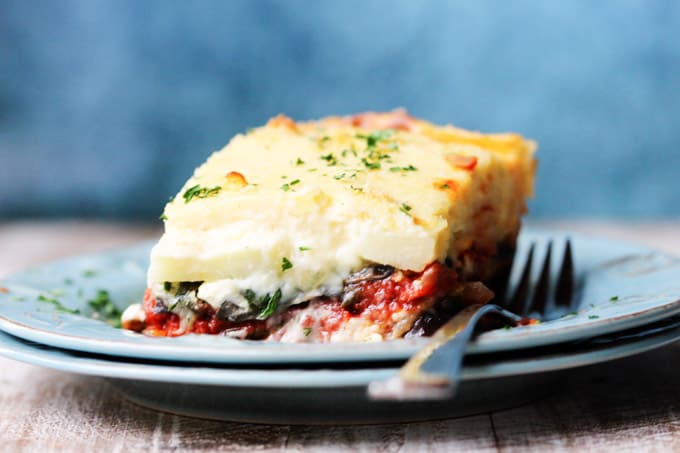 Horizontal shot of a vegetarian moussaka on a blue plate with fork