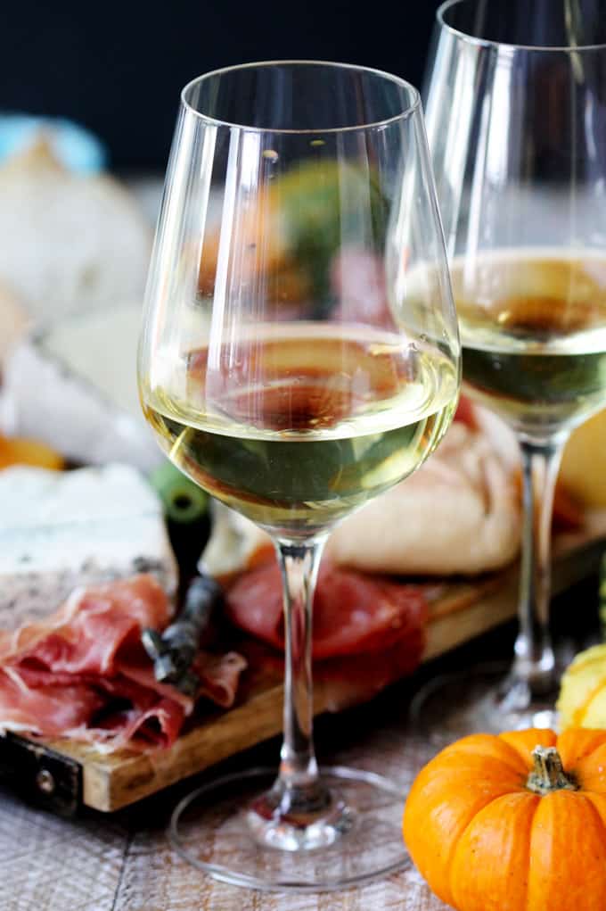 Two glasses with Italian white wine and meat with cheese board