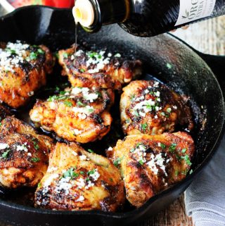 Olive Oil Chicken Mediterranean Style in a skillet with oil pouring over