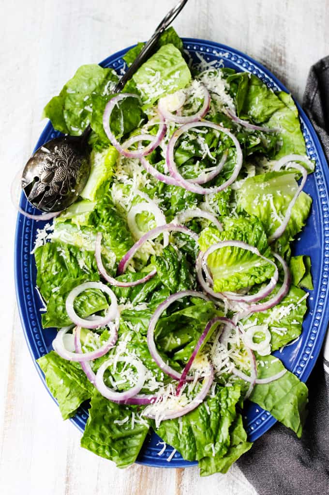 Simple green salad on a blue plate with towel on a side