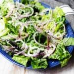 Simple green salad on serving blue plate with kitchen towel on a side