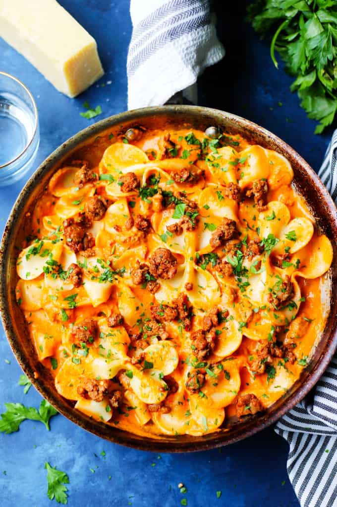 Pasta Alla Vodka with Spicy Sausage in a skillet with cheese and water on a side