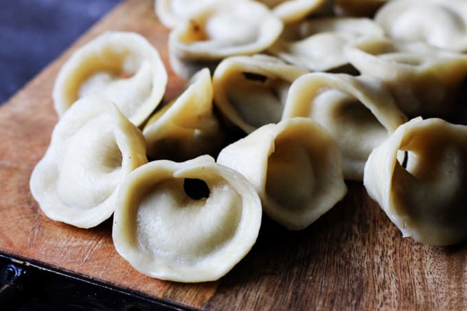 In Poland Mushroom Pierogi called "Uszka" are traditionally served in Borscht on Christmas Eve. They're made from both dry and fresh mushrooms, and a simple pierogi dough of flour, water, milk, and butter. They're beautiful and easier to make than you'd think. Mushroom pierogi Uszka on a board