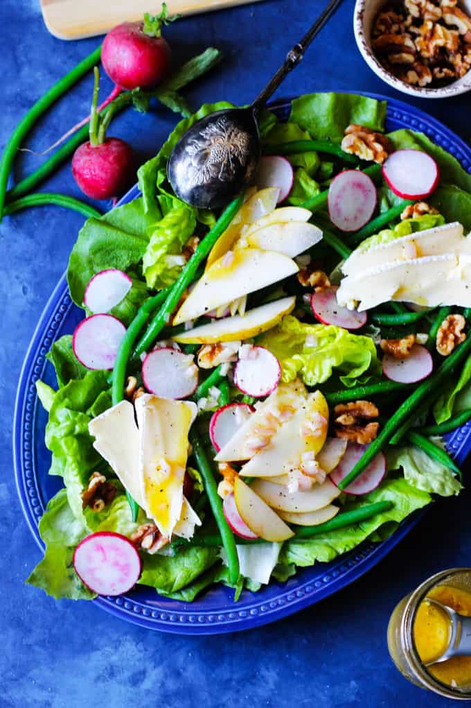 French Salad with Brie and Pears is a wonderful option for those nights when you want to eat a salad but you desire a bit more than just a simple Green Salad. This French Salad recipe is perfect when you want to eat low carb meal without sacrificing on taste and nutrition. Butter lettuce, French green beans, radishes, and pears add a healthy dose of vitamins; and walnuts - give you some healthy fats; and finally the brie cheese - will provide you with needed protein. This salad is naturally gluten-free, and oh so delicious! French Salad with Beans, Radishes, Cheese, Pears on a blue serving plate