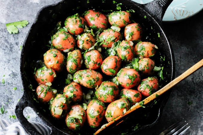 Parsley Potatoes are very easy to make. They very fragrant and filling, yet you only need 4 ingredients to make them! It's a perfect side dish for any meat or fish. Overhead shot of parsley potatoes in a skillet with wooden spoon