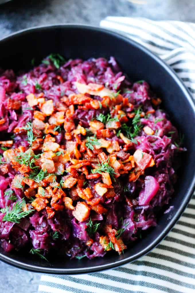 Rotkohl - German Braised Red Cabbage in a black bowl with bacon bits on top