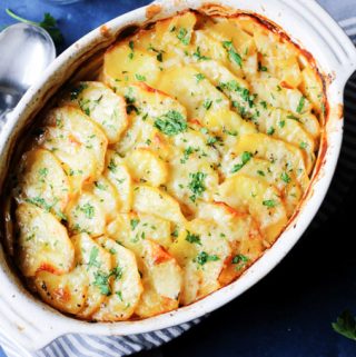 Boulangere Potatoes in white baking dish with spoon on a side